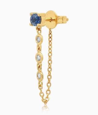 Gold earring with a sapphire stud and chain dangling down
