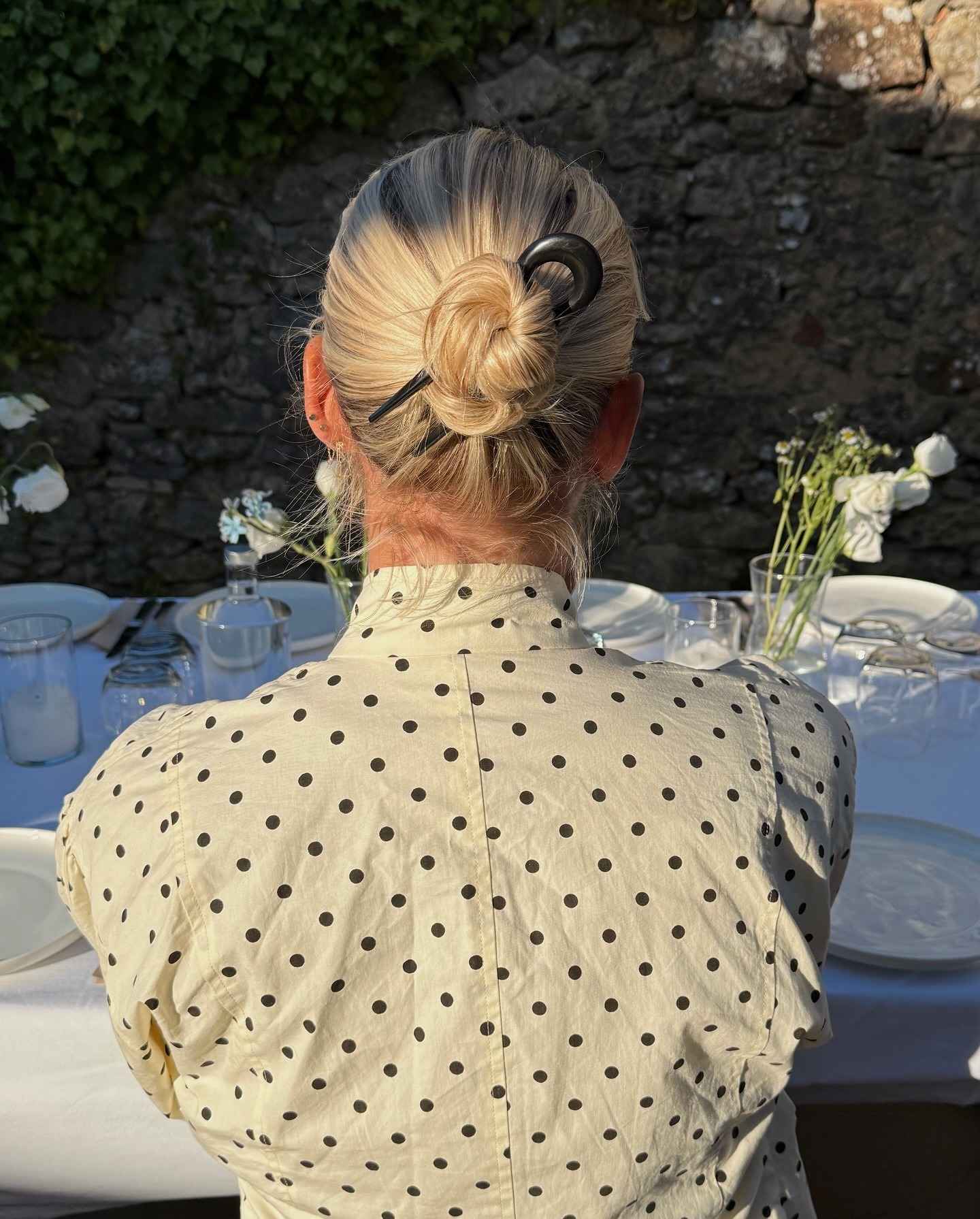 A woman wearing her bob hairstyle in a bun secured in place with a hair pin