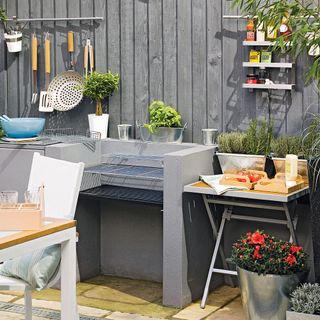 bbq with grey outdoor kitchen white chair and potted plants