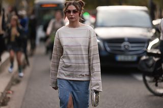 A fashion week guest seen wearing an acne studios long shirt, a gucci bag and a long jeans skirt, outside Acne Studios during Paris Fashion Week on September 28, 2022 in Paris, France.