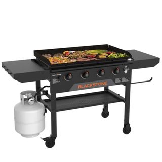 A Blackstone 36 Omnivore Griddle w Folding Shelves cooking meat and vegetables 