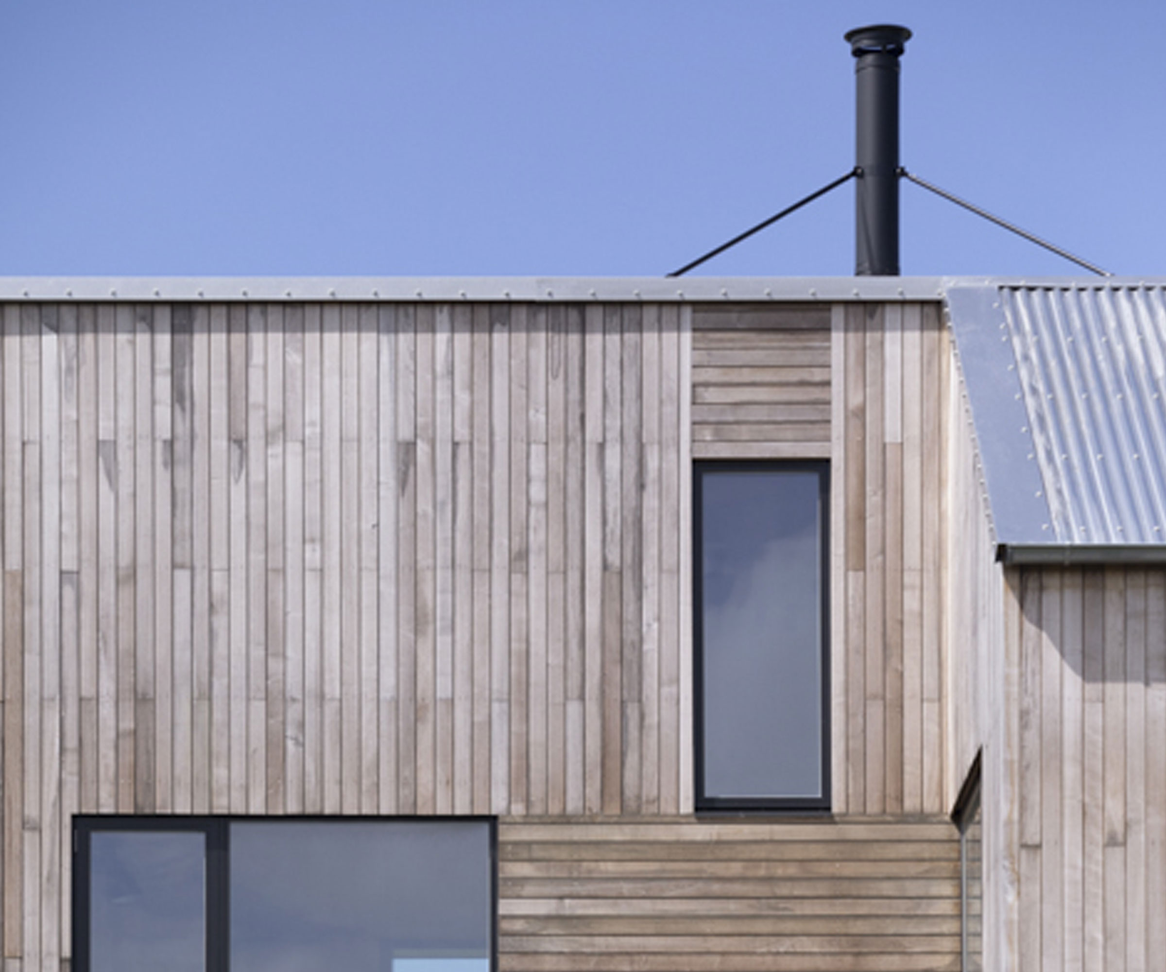 Brimstone Ash Timber Cladding on contemporary flat roof home with black framed windows
