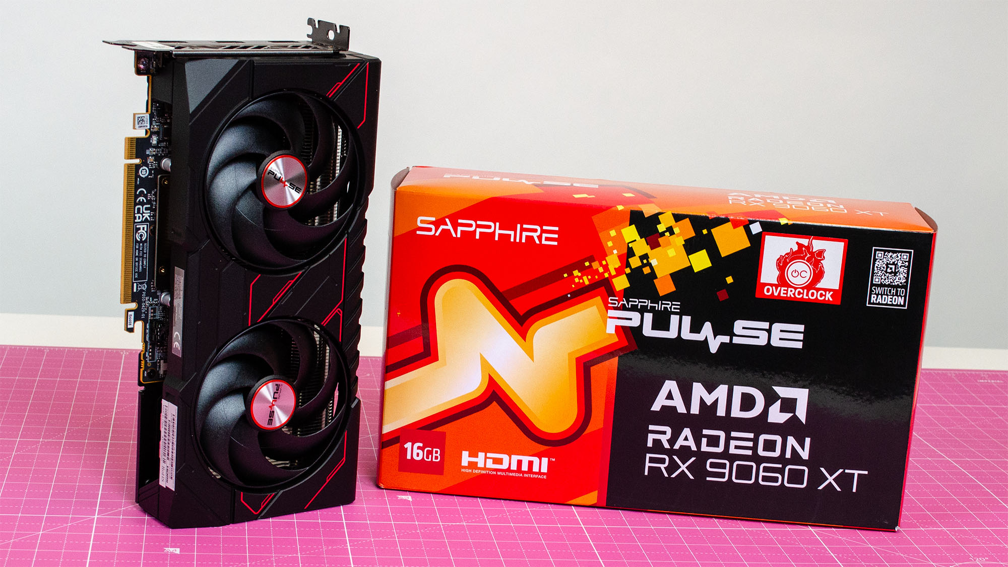 An AMD Radeon RX 9060 XT next to its retail packaging on a table