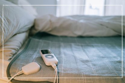 close up of hands turning on an electric blanket laid on a double bed