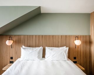 An example of a Mollie's hotel room in Oxfordshire, United Kingdom with green wall paint, double bed with mattress and pillows, wood paneling and bedside lighting fixtures