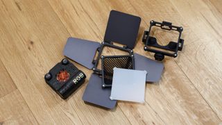 Zhiyun FIVERAY M20C LED panel held and accessories laid out on a wooden floor