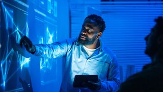 A male office worker presents data on a big display in the office