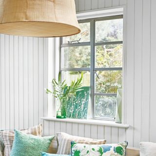 Sage green coloured metal window in living room, surrounded by white panelled walls