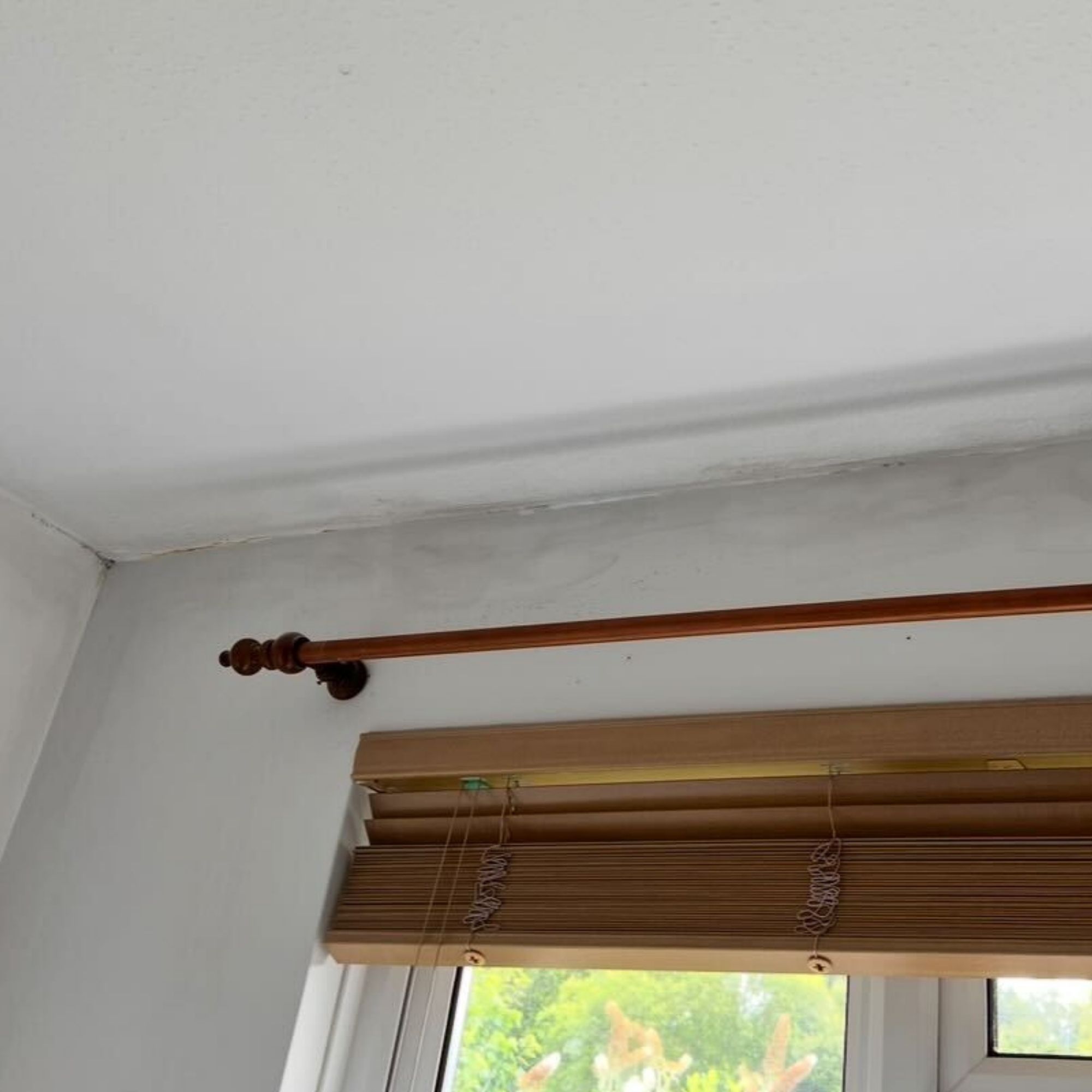 A white wall and ceiling near a window, showing candle smoke damage.
