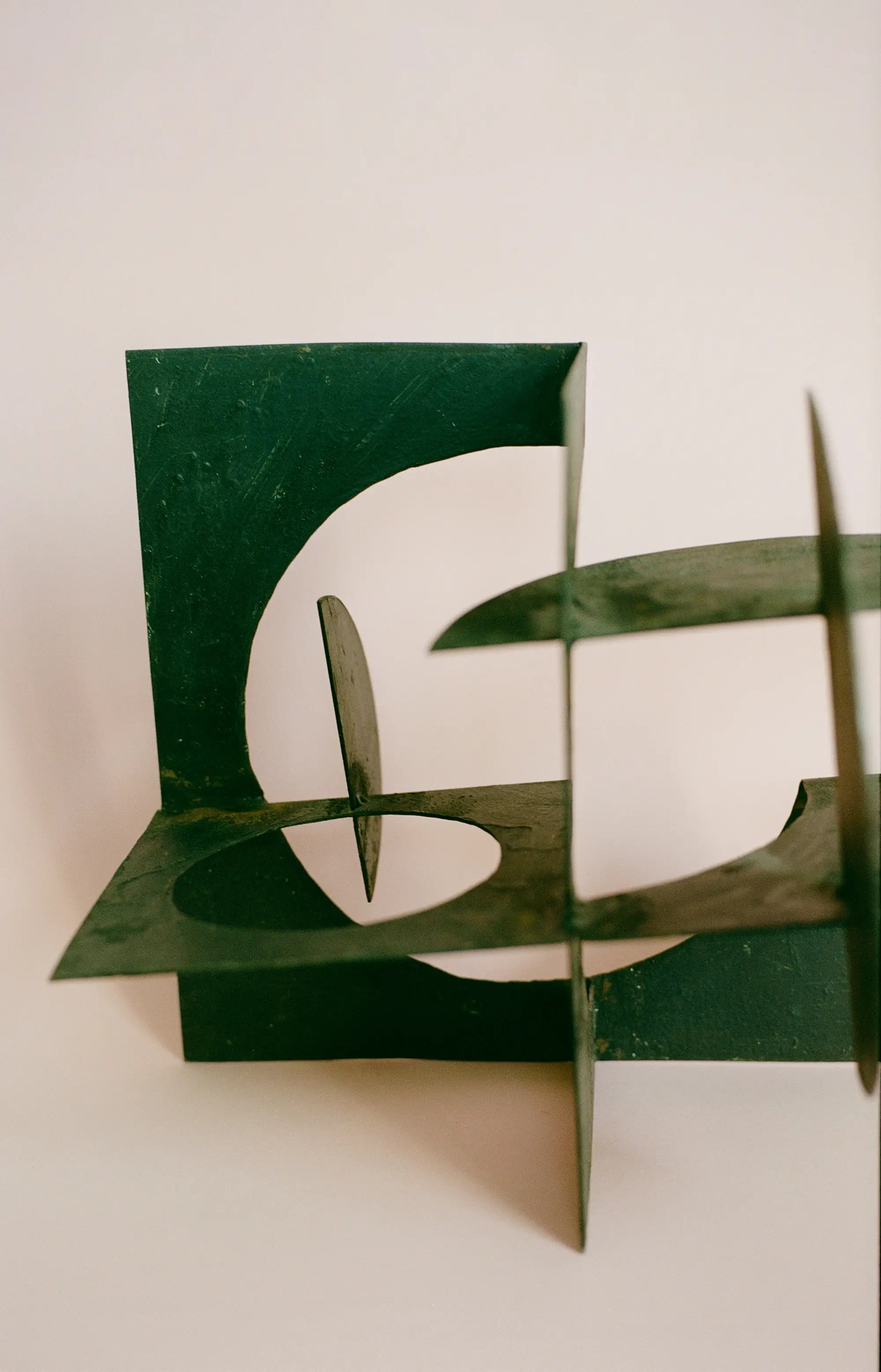 A geometric metal sculpture seen against a blank background.