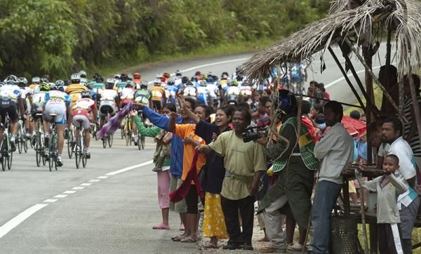 The peloton are encouraged on by locals beneath a typical road-side shelter during stage four.