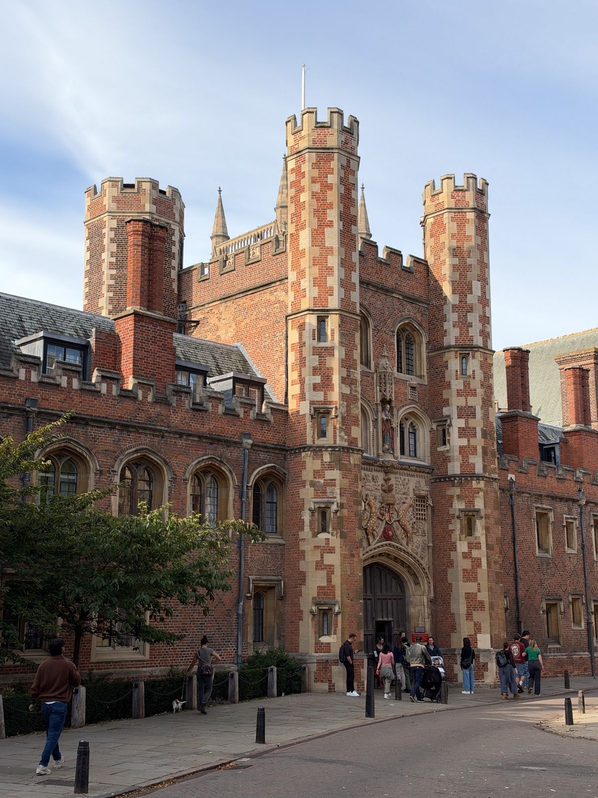 Grand red-brick historic building with crenellated towers, Gothic windows, and an ornate arched entrance.