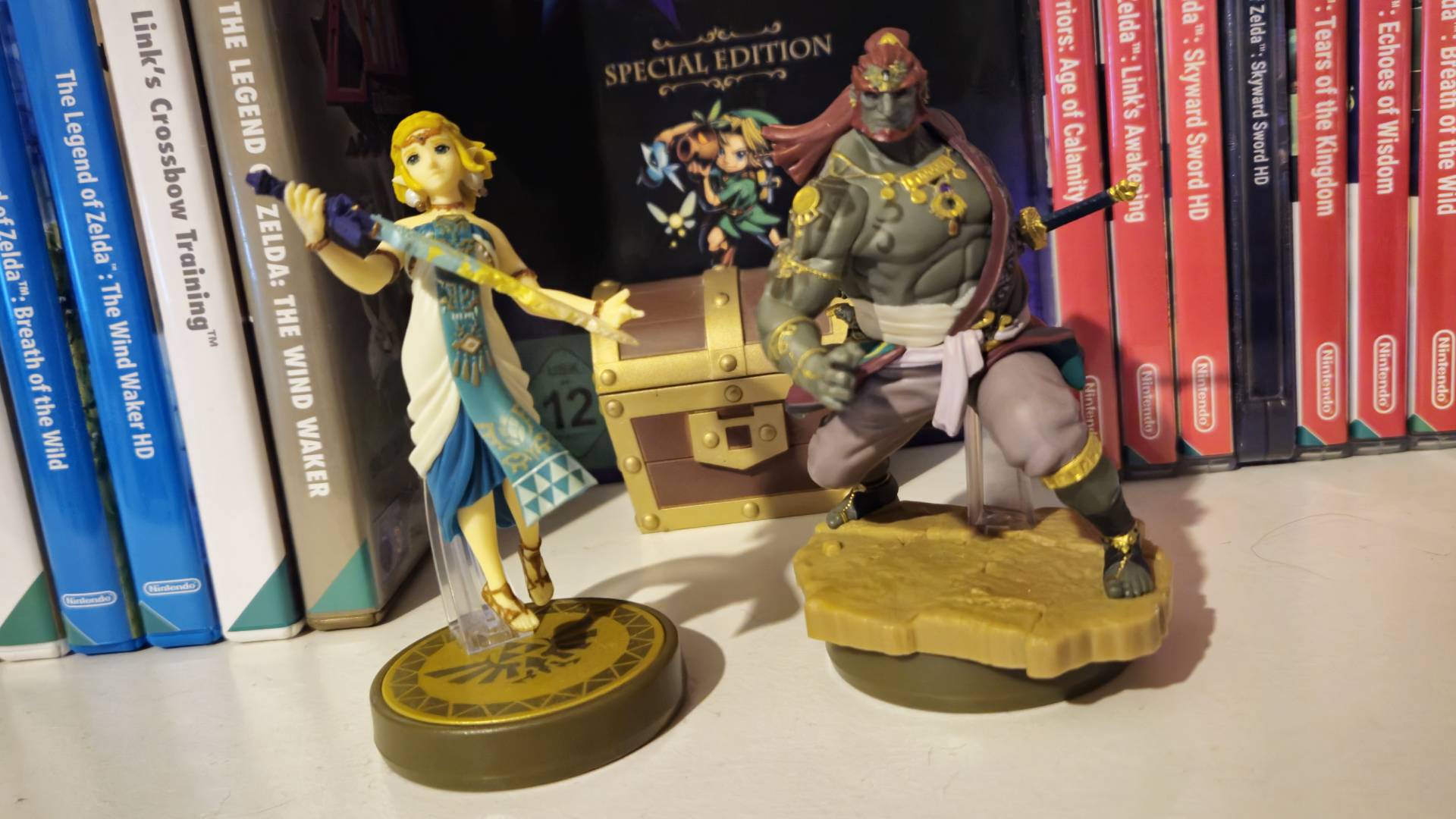 Una imagen del amiibo real Reina Zelda y Ganondorf sentados en un estante con juegos de Zelda detrás de sus lágrimas.