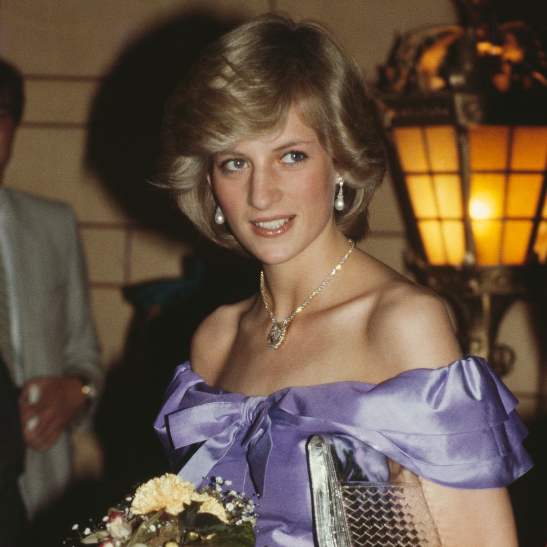 Princess Diana wearing a pale purple off the shoulder dress holding flowers