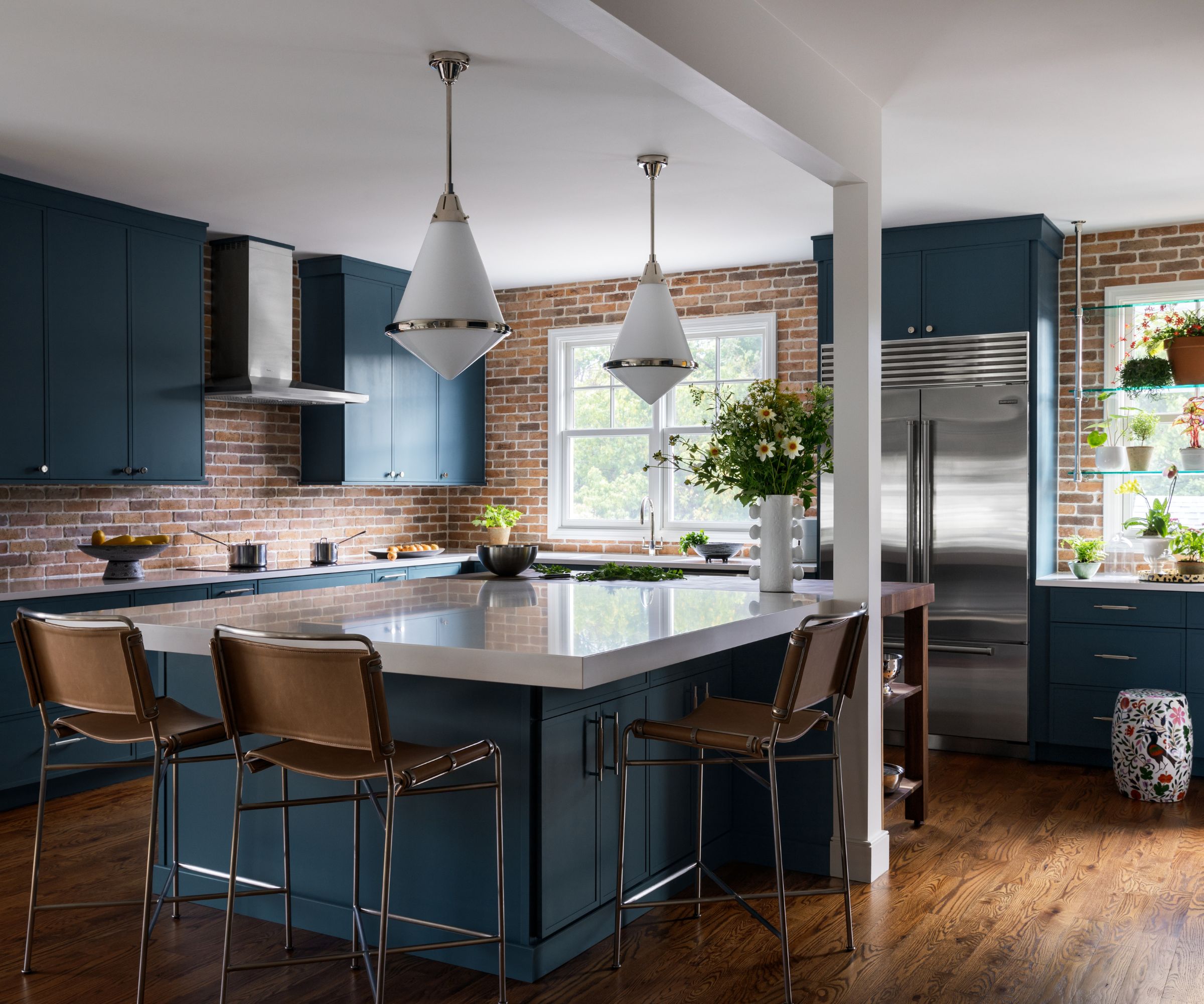 Kitchen with blue cabinetry, a brick backsplash and a wooden butchers block attached to a white marble topped island