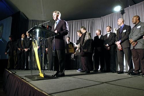 Greg LeMond is surrounded by 18 members of the 1984 US Olympic team during a presentation of a plaque to Eddie B at the awards.