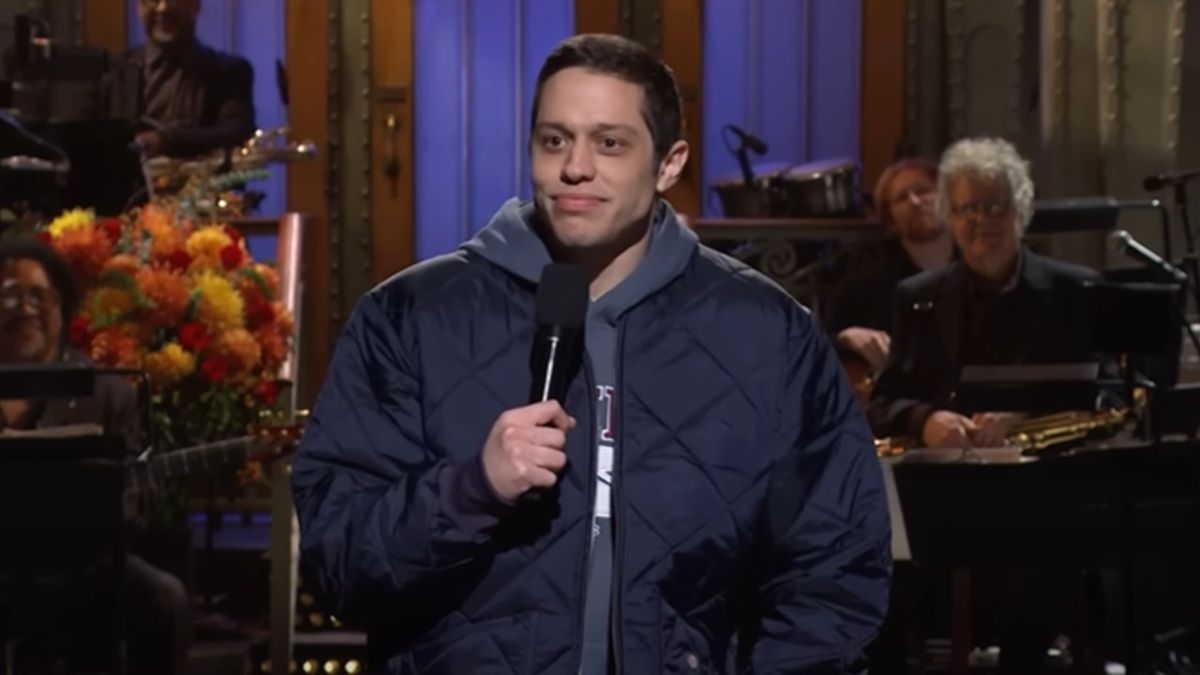 Pete Davidson holding up a mic with his left hand during his Monologue on SNL.