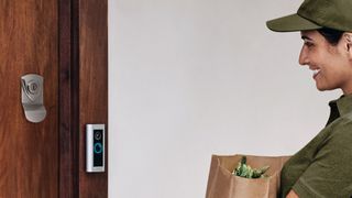 Woman holding groceries in front of a front door with a ring video doorbell