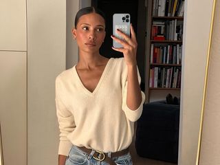 Influencer wearing a cream V-neck sweater and jeans.