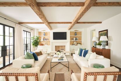 A light neutral living room with accents of blue and green, exposed beams and traditional setting