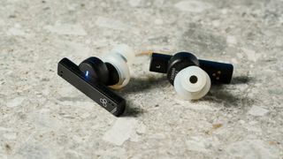 a photograph of black earbuds by final with a long, angular stem and black casing, silicone ear tips