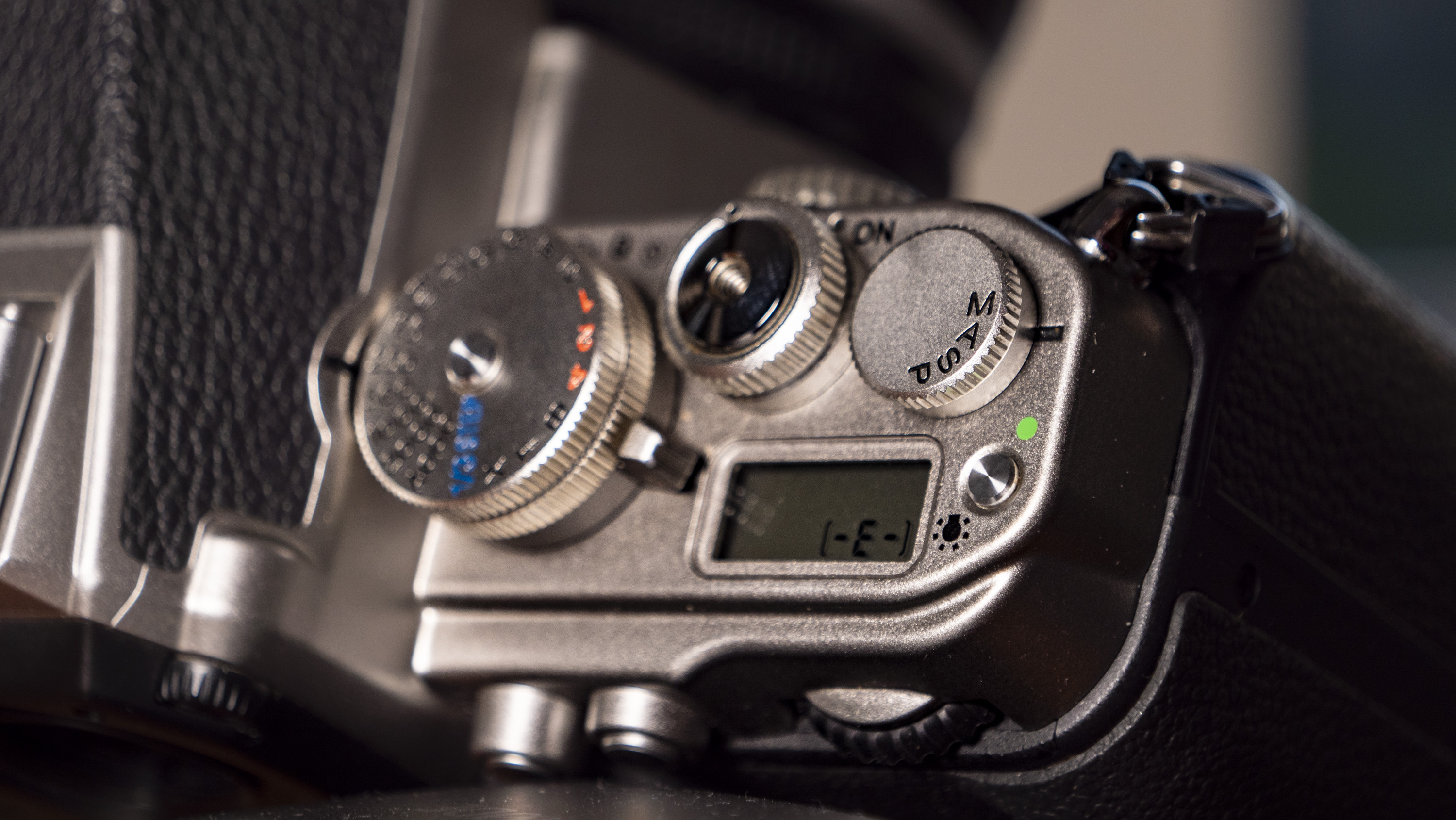 Nikon Df DSLR camera on a wooden surface by large window, with dusk light