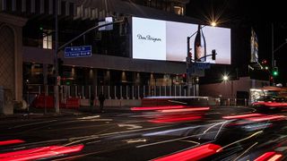 A billboard lights up the Sunset Strip as car lights zoom by.