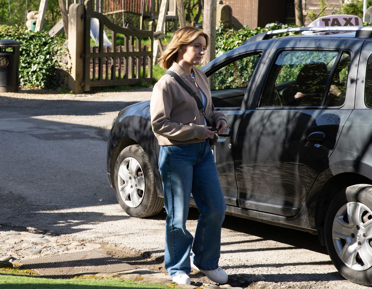 Ella standing by a car in Emmerdale 