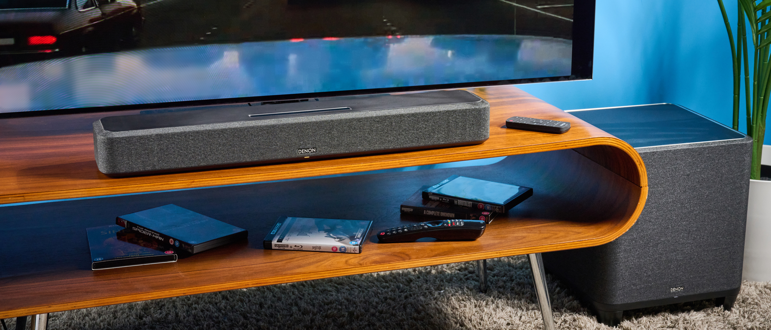 the denon home sound bar 550 with a gray mesh casing and touch controls for bluetooth on the top with a remote and smart home integration