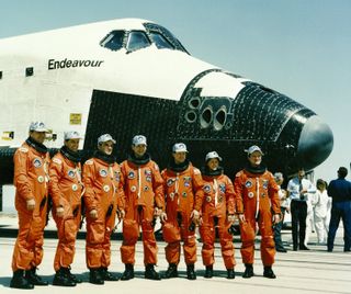 The STS-49 crew members pose near Endeavour after landing. Pictured left to right are: mission specialist Richard J. Hieb, pilot Kevin P. Chiltin, commander Daniel C. Brandenstein, and mission specialists Thomas D. Akers, Pierre J. Thuot, Kathryn C. Thorn