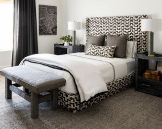 gray bedroom with geometic patterned bed and gray bench
