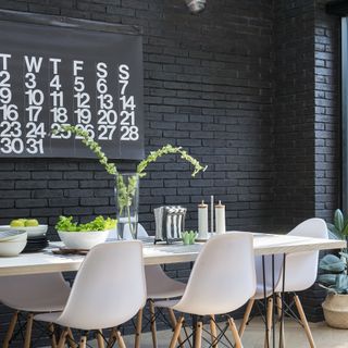 dining area with wooden floor and black painted brick wall with white table