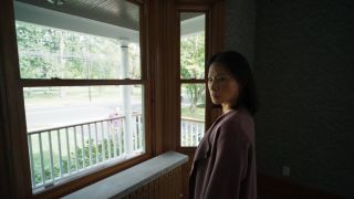 lucy liu wears a sweater and looks nervous standing by a window in the movie presence