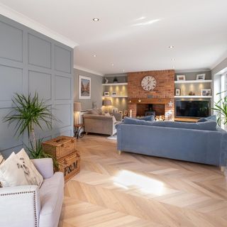 Lounge with brick fireplace, grey sofa, blue sofa and wall shelves