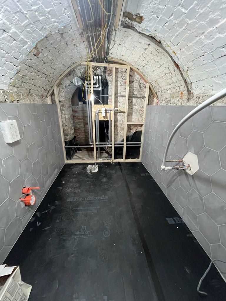 The bathroom in the air raid shelter being built with the stud wall exposed at the end of the room