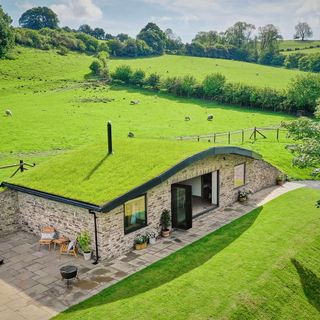house exterior with open lawn area and stone walls