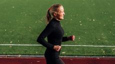 Woman happily running along along track after learning how to start running as a beginner