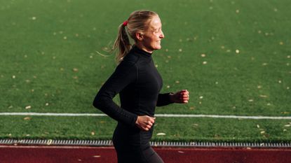 Woman happily running along along track after learning how to start running as a beginner