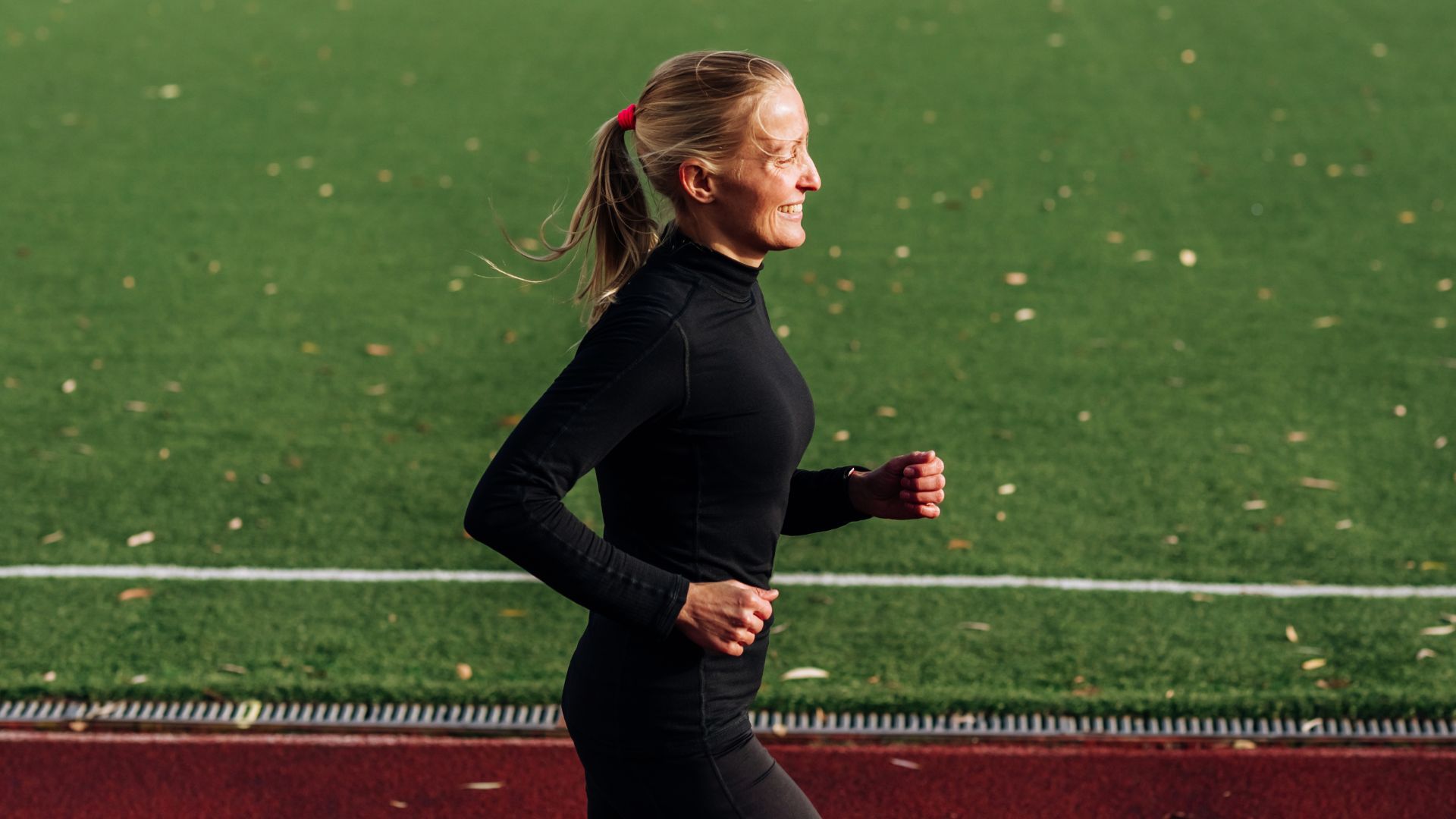 Woman happily running along along track after learning how to start running as a beginner