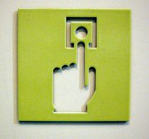 Close up view of a green panel with a cut out design of a hand with one finger touching a circle and square shape above