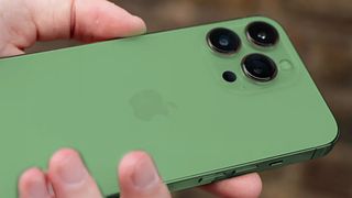 En hand som håller upp en iPhone 13 Pro med en redigerad grön färg på baksidan.