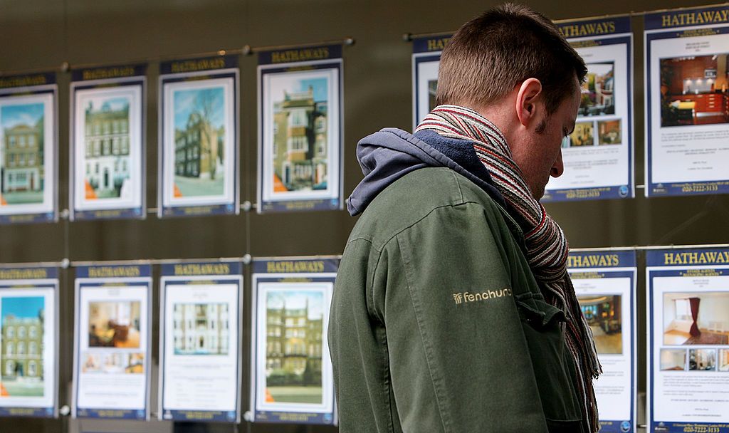 Man looking at houses for sale in estate agent window