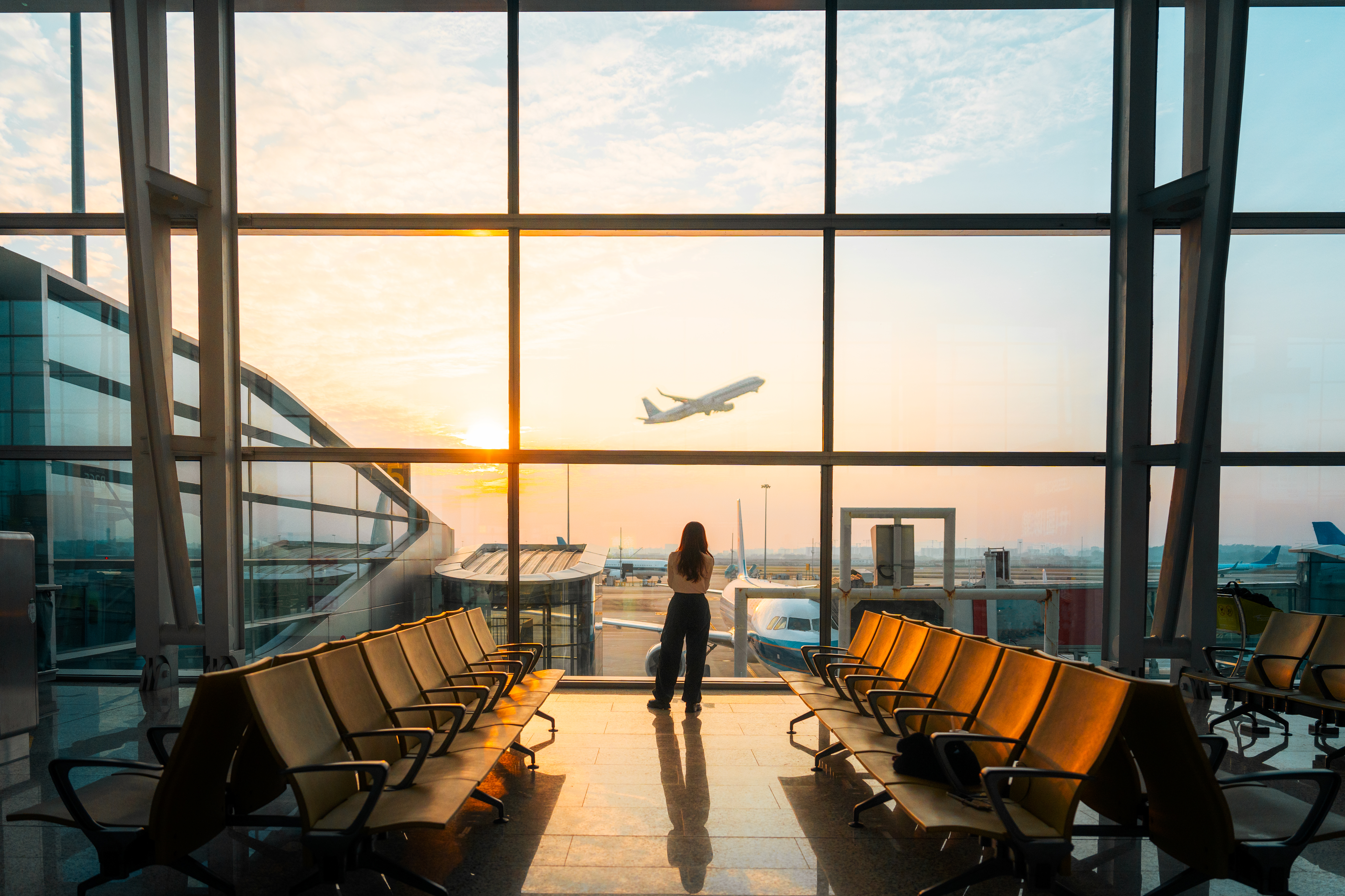 A woman looks out at the tarmac at an airport
