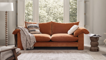 orange sofa in a white living room with large windows