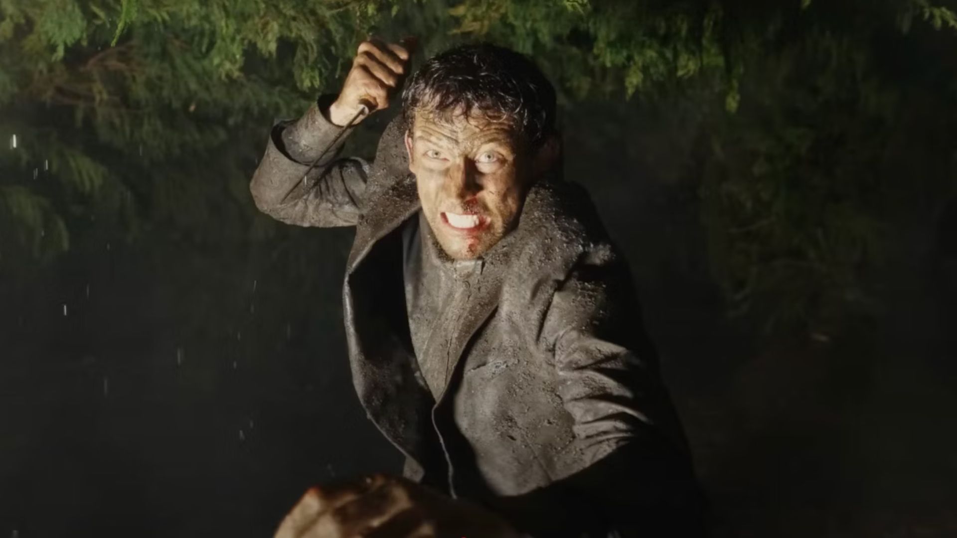 Josh O&#039;Connor covered in mud raises a knife above his head