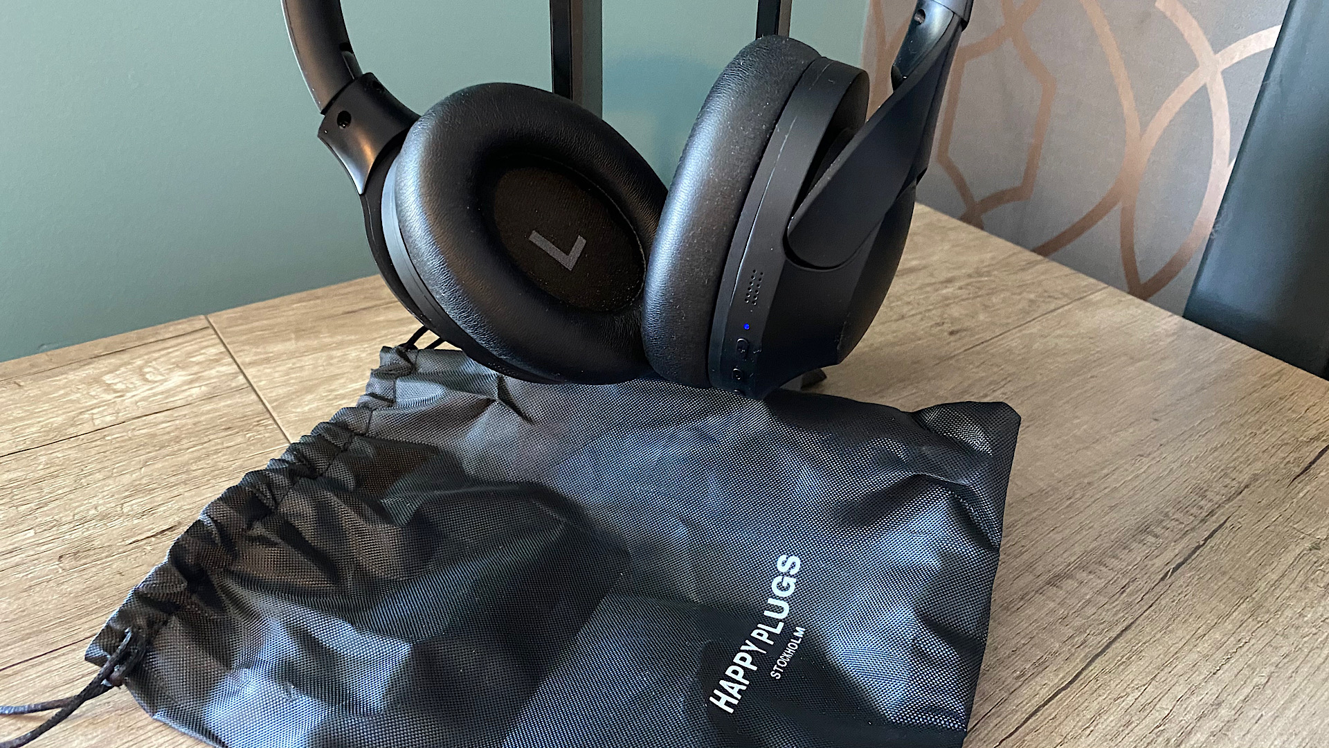 Happy Plugs Play Pro headphones and their carrying bag on a wooden surface