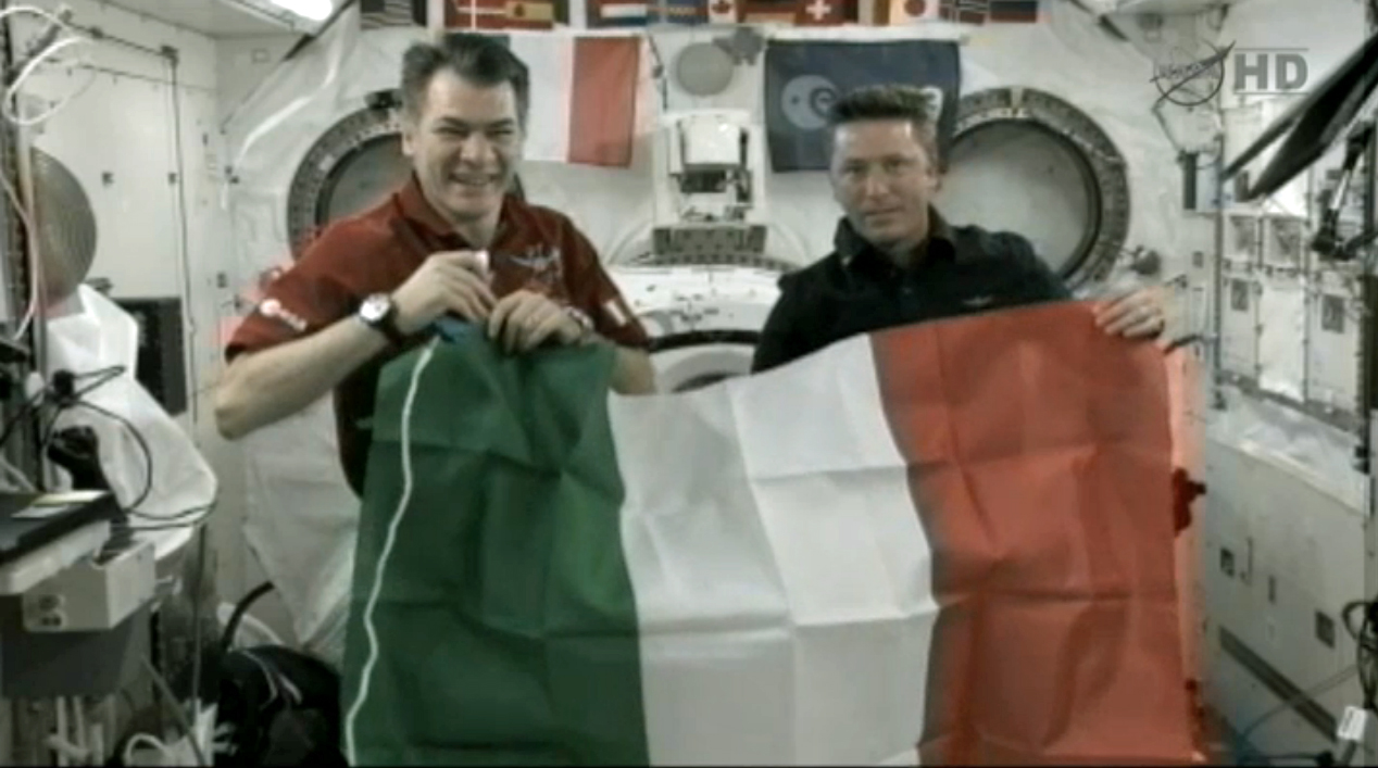 Italian astronauts Paolo Nespoli (left) and Roberto Vittori (right) wave an Italian flag on the International Space Station during a conversation with Italy&#039;s President Giorgio Napolitano on May 23, 2010 during NASA&#039;s Endeavour shuttle mission.