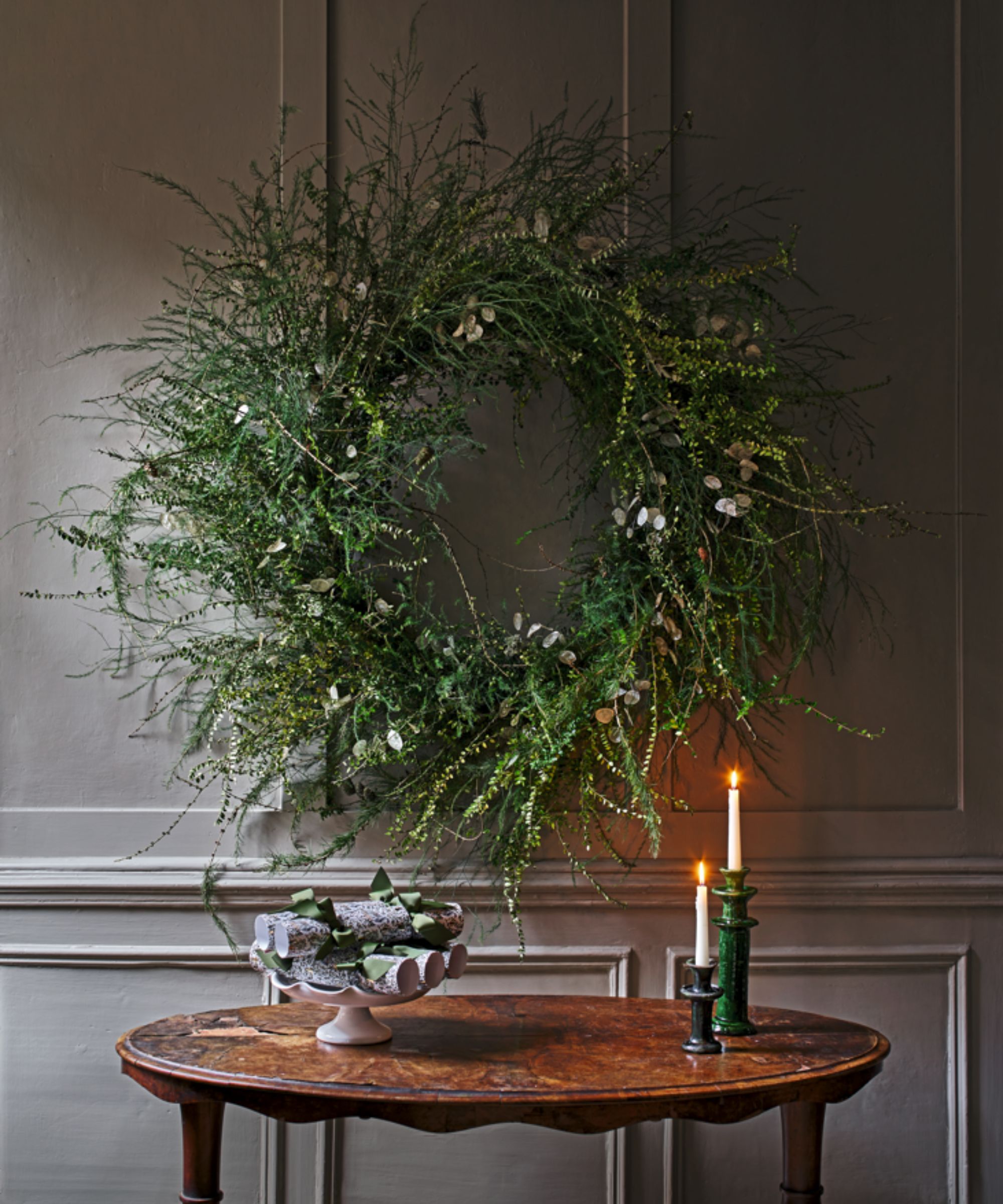 Christmas wreath and taper candles on a small round table