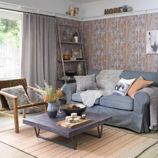 living room with bamboo printed wall and grey sofa set with wooden teapoy