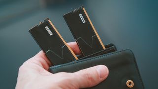 Black DDR5 RAM memory modules placed inside a black wallet held in hand, symbolizing high cost of computer memory.